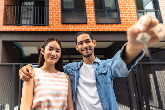 Young Couple New House Keys Buy Real Estate Home. Excited Biracial Family Buyers Close Deal Or Agreement  Buy First House.people Holding Key Of New House.