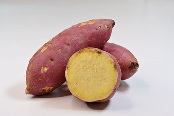Cross-section of Japanese sweet potato and whole tubers, on white background