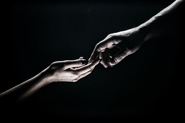 Fototapeta na wymiar Two hands reaching toward. Tenderness, tendet touch hands in black background. Romantic touch with fingers, love. Hand creation of adam.