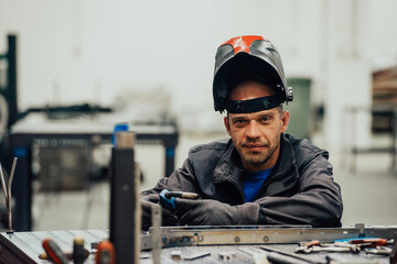 Professional Heavy Industry Welder Working Inside factory, Wears Helmet and Starts Welding. Selective Focus