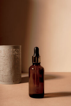 Brown Glass Cosmetic Serum Bottle On Light Beige Background With Shadows. Close Up