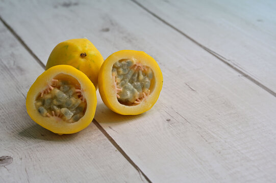 Yellow or golden passion fruit, whole and cut, on timber table background