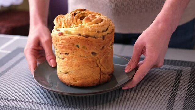 young woman puts fresh baked easter cake cruffin on kitchen table