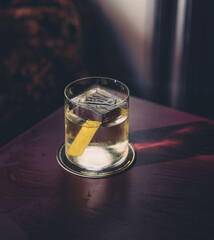 Tasty cocktail with a big ice cube and a lemon zest inside