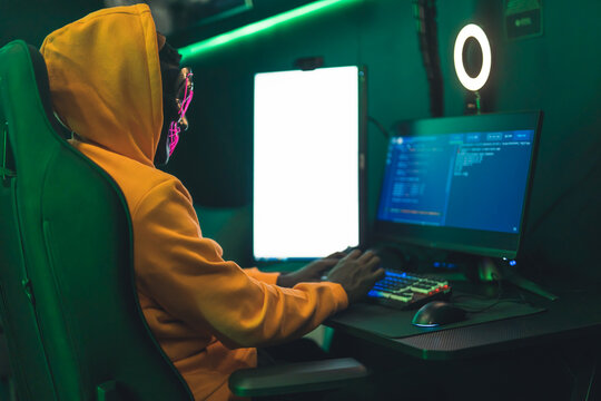 hacker in an orange hood and with a mask hacking databases medium shot cyberterrorism concept indoors . High quality photo