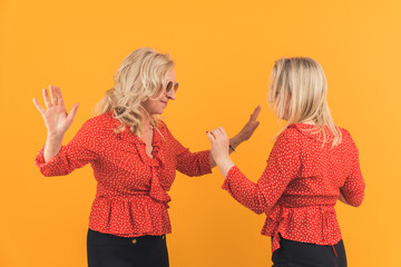 family generation concept, mom and her daughter dancing together in the studio, isolated orange background. High quality photo