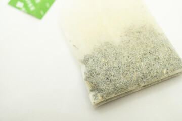 Teabag with green label. Isolated on white background. Close-up of tea bag. 