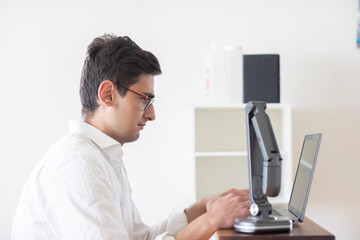 Junger Mann arbeitet in einem Büro mit technischen Geräten im Hintergrund