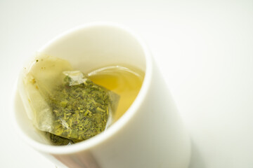 Green tea bag in a cup. Cup of aromatic green tea on white background. Cup with green tea in isolated.