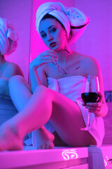 girl with a glass of wine in the bathroom in neon light