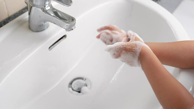 Girl washing hands with soap to prevent virus and germs.