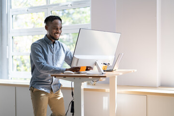 Man Using Adjustable Height Standing Desk In Office