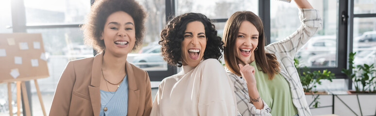 Cheerful multicultural businesswomen standing in office, banner.