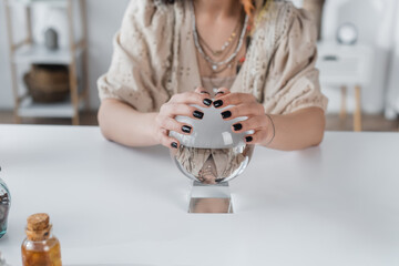 Cropped view of blurred medium touching glass orb on table.