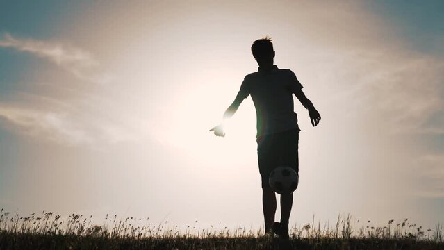 Boy with soccer ball. Child in park plays at sunset.Boy juggles soccer ball.Child dream of football match.Sports training in park. Sportsman is in control of ball. Child juggles ball.Healthy lifestyle