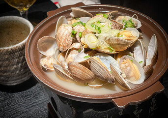 Japanese clams cooked in broth with spring onions and ginger on top