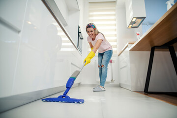 A housewife using mop for kitchen floor.