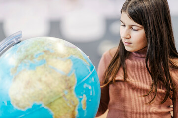A schoolgirl pointing at the globe on geography class.