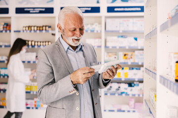 A senior man reading instructions for a pills he wants to buy at pharmacy.