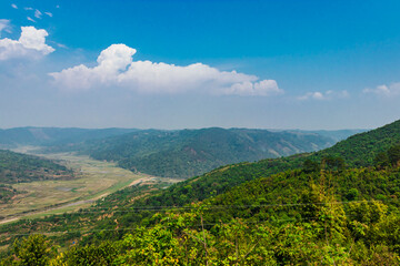 mountain range covered with green forests and bright blue sky at morning from flat angle