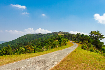 Fototapeta na wymiar isolated road with mountain covered with green forests and bright blue sky at morning