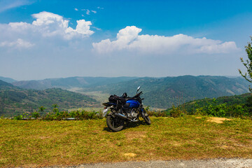 Fototapeta na wymiar isolated motorcycle parked at mountain top with bright blue sky