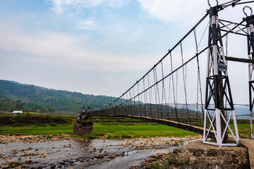 isolated iron suspension bridge old with misty mountain background at morning