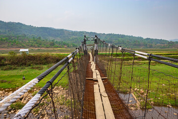 Fototapeta na wymiar isolated iron suspension bridge old with misty mountain background at morning