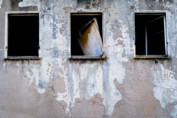stary opuszczony budynek z rozbitymi oknami i zdartą farbą ze ściany - obrazy, fototapety, plakaty