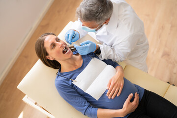 Male Dentist Treating Teeth Of Young Pregnant Woman
