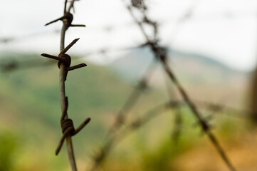 Closeup of barbed wire in a hilly landscape