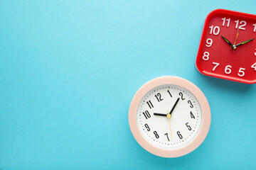Fototapeta na wymiar Pink and red wall clock on blue background. Vertical photo
