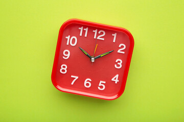 Red wall clock on green background. Space for text