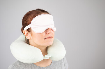 Caucasian woman with travel pillow and sleeping mask isolated on white background.