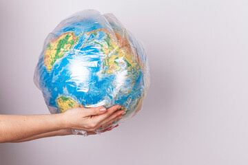 Environmental protection. Tarnishing the planet. A woman holds in her hands the planet Earth in the form of a globe in a plastic bag on a white background
