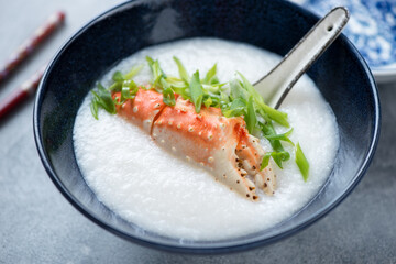 Close-up of crab congee or a type of asian rice porridge served in a dark-blue bowl, selective focus