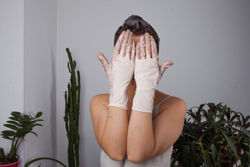 a woman dyes her hair at home on her own. Hands in dirty gloves in hair dye stretched out into the frame