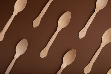 Eco wooden reusable spoon pattern on brown background. View from above. Top view. Flat lay.