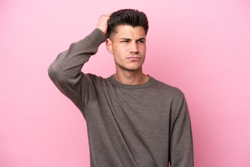 Young caucasian man isolated on pink background having doubts while scratching head