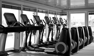 Staying fit with cardio fitness equipment and treadmills in gym or fitness center on modern cruiseship or cruise ship liner - obrazy, fototapety, plakaty
