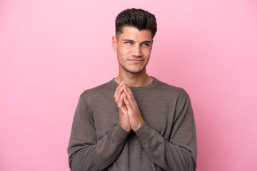 Young caucasian man isolated on pink background scheming something
