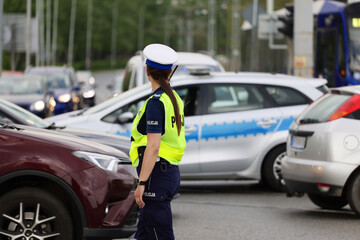 Policjantka ruchu drogowego kieruje ruchem ma skrzyżowaniu dróg w mieście.  - obrazy, fototapety, plakaty