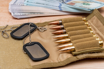 Army identification medallions on American dollar bills, bandolier with live ammunition. Concept: military special operation, arms supplies, financing of war, lend-lease, sale of weapons.