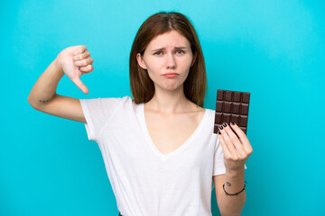 Young English woman isolated on blue background taking a chocolate tablet making bad signal