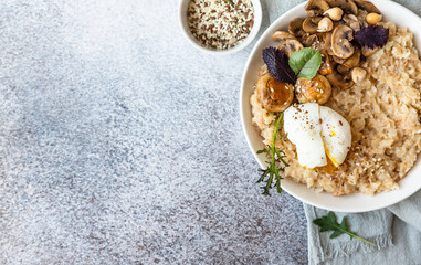 Savory porridge for breakfast. Oatmeal or spelt flakes with poached egg, fried mushrooms and herbs....