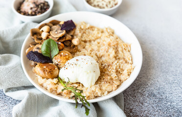 Savory porridge for breakfast. Oatmeal or spelt flakes with poached egg, fried mushrooms and herbs. Healthy food. Keto diet.