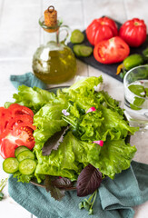 Plate with fresh green salad, grey tiled background. Mix of salad leaves with cucumber, tomatoes and microgreen. Top view.