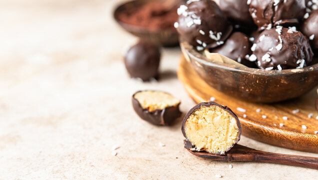 Vegan chickpea and peanut butter candies in chocolate glaze with coconut chips. Energy balls. Healthy raw dessert without sugar.