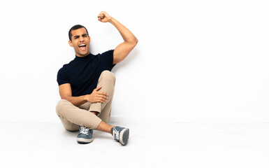 Fototapeta premium African American man sitting on the floor celebrating a victory