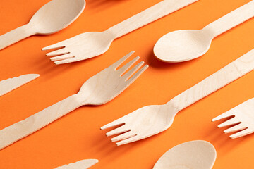 Disposable wooden cutlery on a orange background. Environmentally friendly materials.